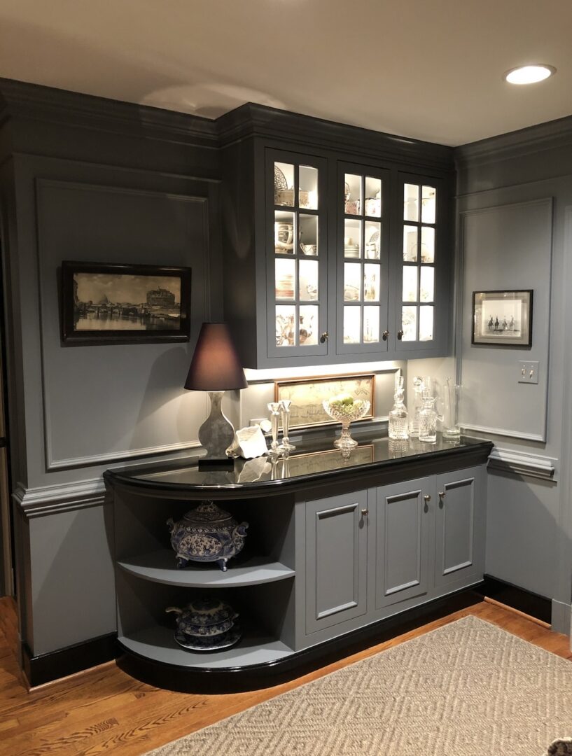 A kitchen with gray cabinets and black counter tops.