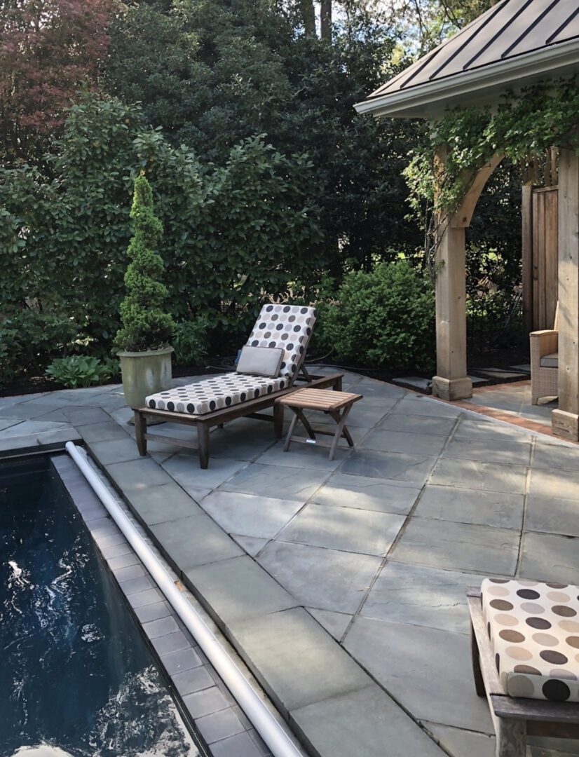 A pool area with an outdoor lounge chair and table.