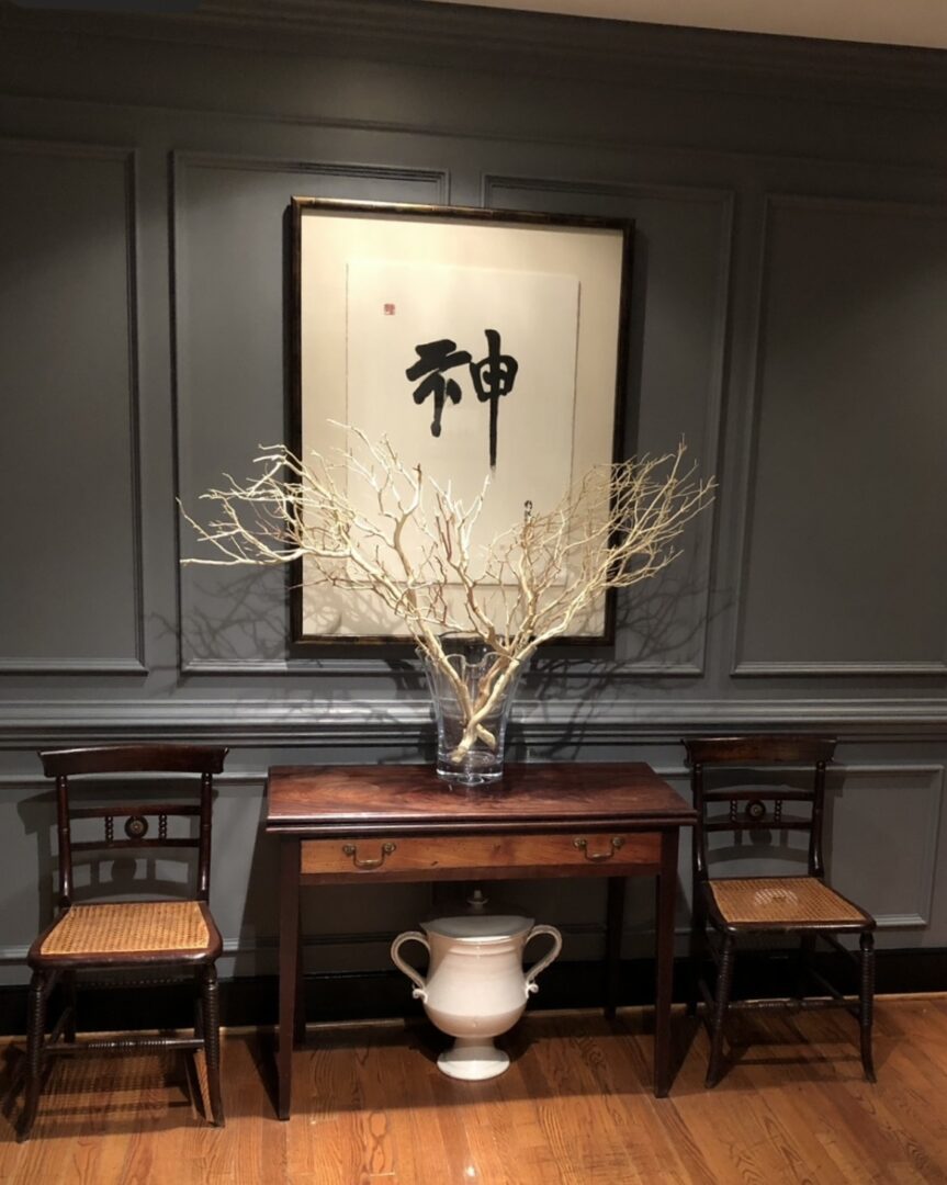 A table with two chairs and a vase on it